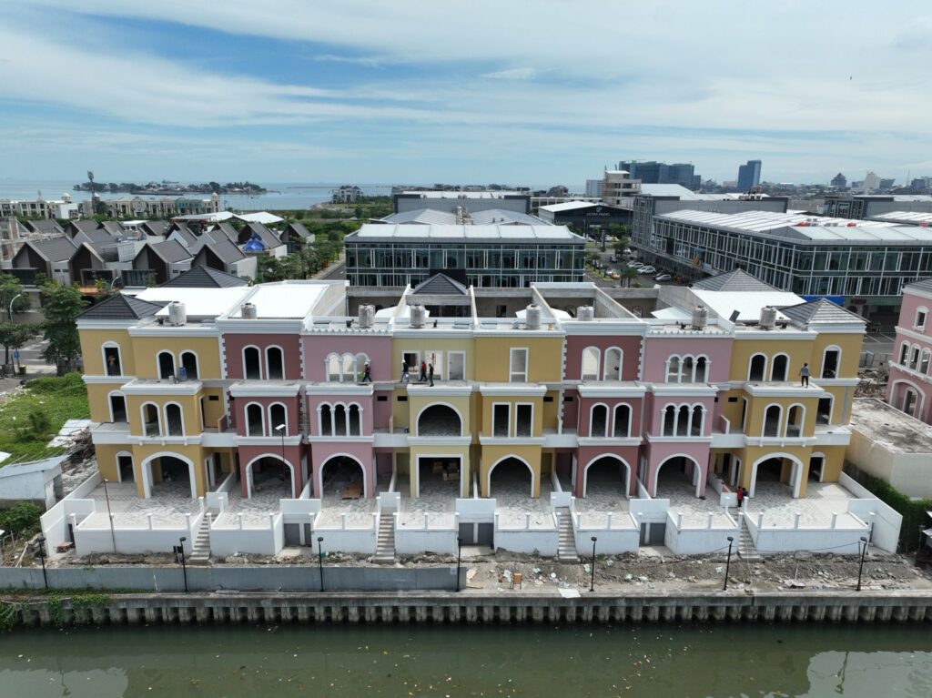 WhatsApp Image 2026-07-17 at 81445 AM 1 - CitraLand City Center Point Indonesia row of pastel colored townhouses with arched doorways along a canal waterfront construction in progress nearby citraland city center point indonesia